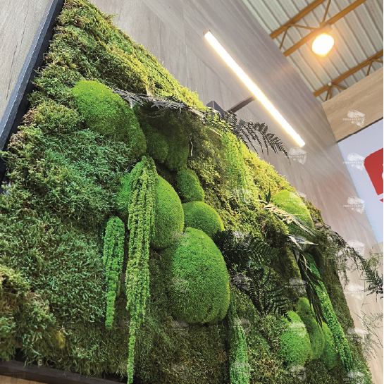 Un homme travaille sur un mur végétal avec le logo "Eiffage" en arrière-plan.