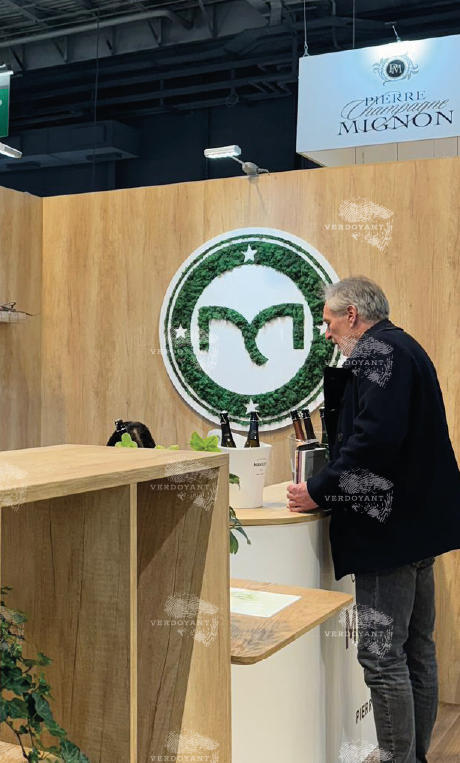 Un homme se tient devant un comptoir avec un logo vert sur un mur en bois.
