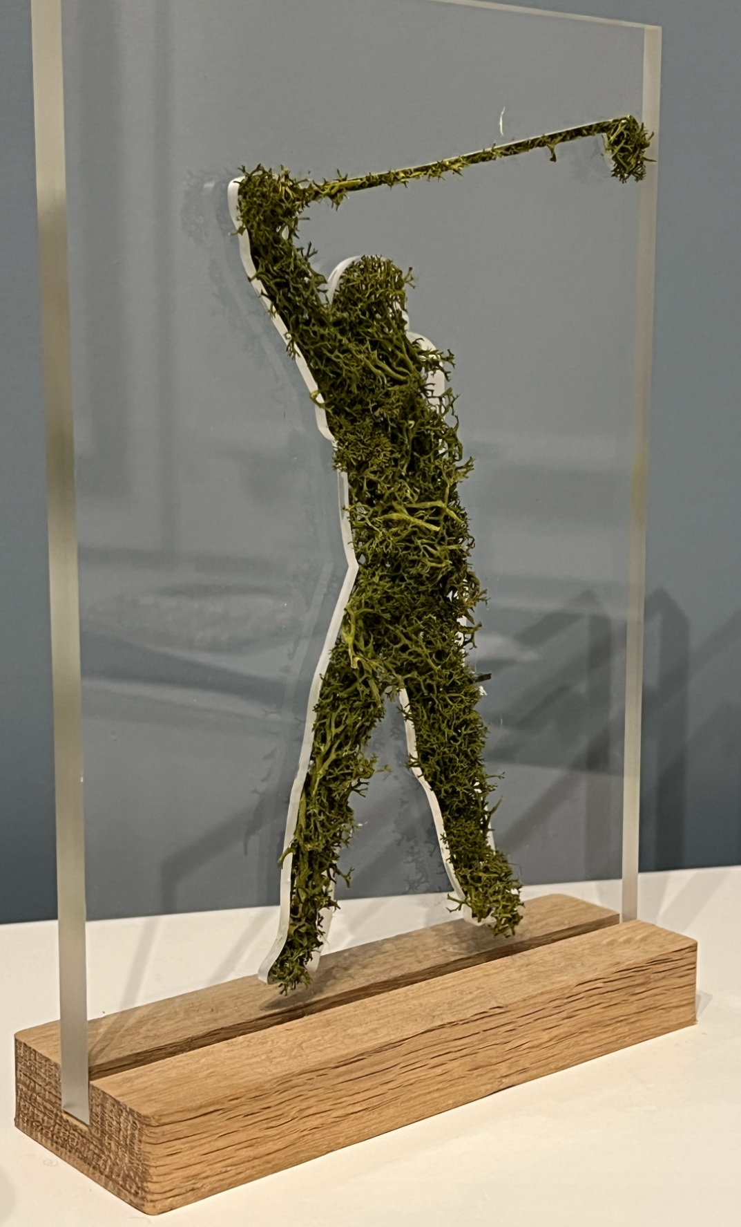 Silhouette d'un golfeur en verdure, sculptée dans un bloc en acrylique sur socle en bois.