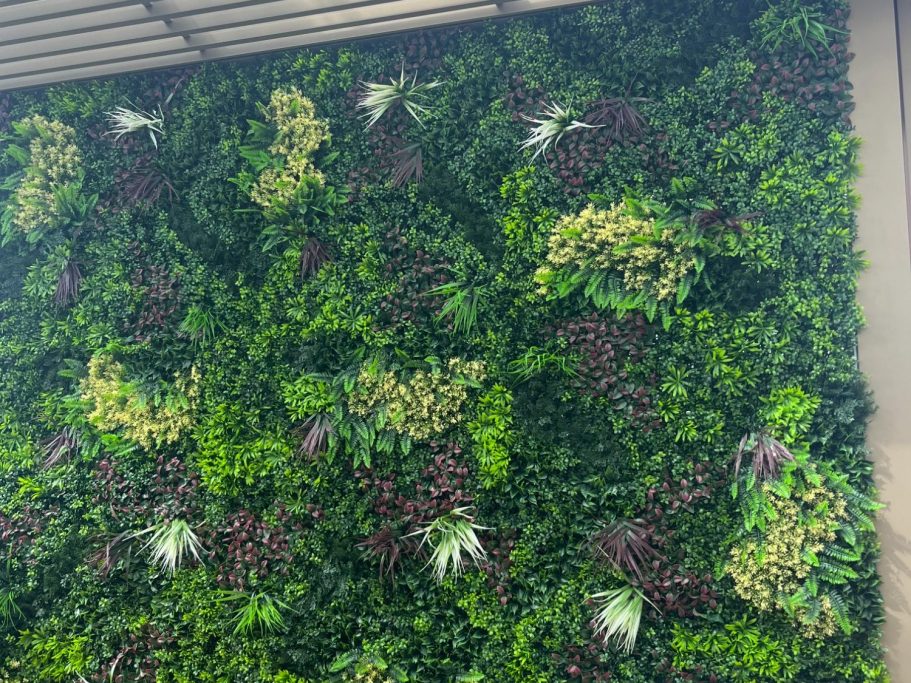 Mur végétal luxuriant avec une variété de plantes vertes et quelques fleurs.