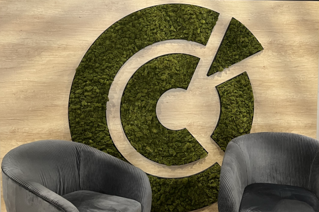 Logo stylisé en vert sur un fond beige, avec deux fauteuils gris à côté.