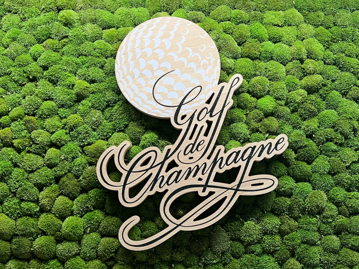 Logo du Golf de Champagne avec une balle de golf sur un fond de mousse verte.