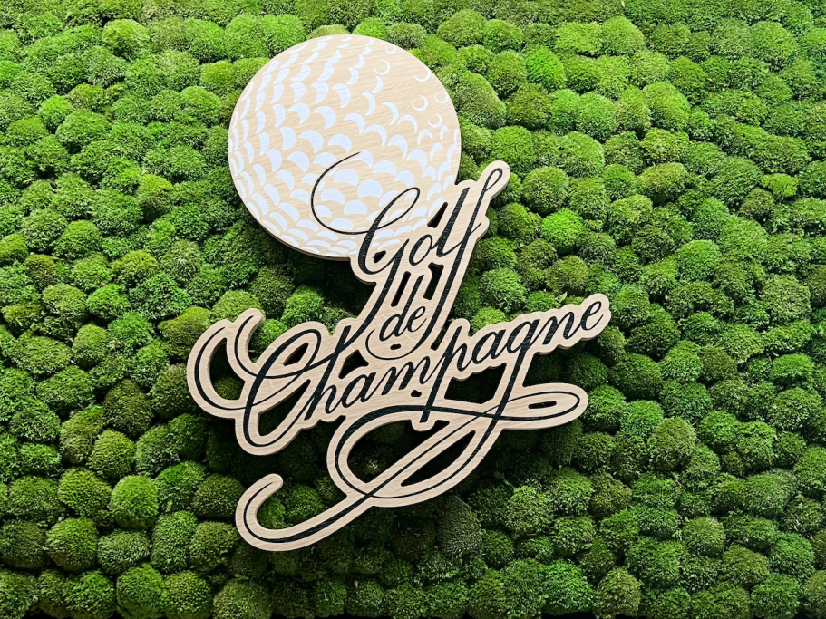 Logo de Golf en Champagne avec une balle de golf sur un fond vert mousse.
