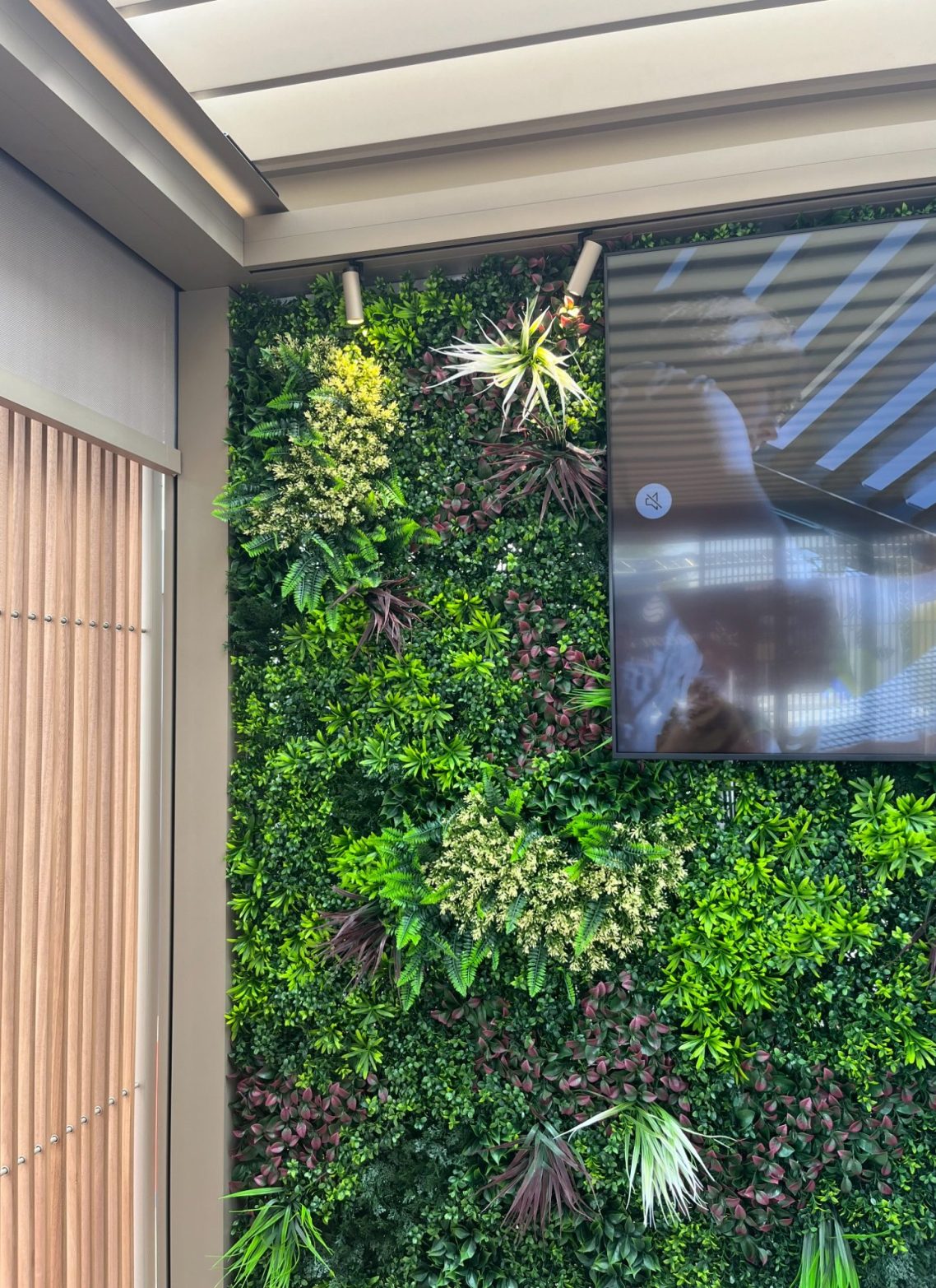 Mur végétal avec des plantes vertes et un écran intégré.