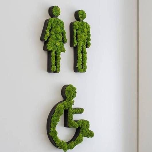 Panneau indiquant des toilettes avec silhouettes en mousse verte.