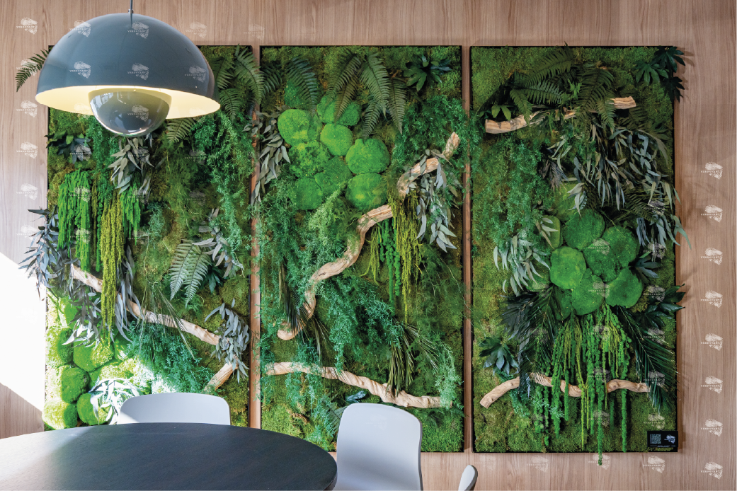 Mural végétal vert avec des feuilles et des branches, décorant un mur intérieur.