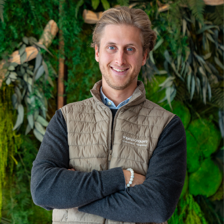 Homme souriant, les bras croisés, devant un mur végétal stabilisé.