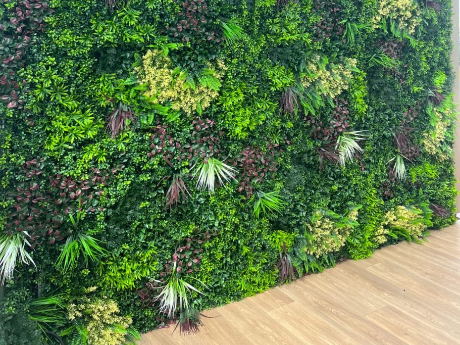 Mur végétal luxuriant avec diverses plantes vertes et touches de couleurs.