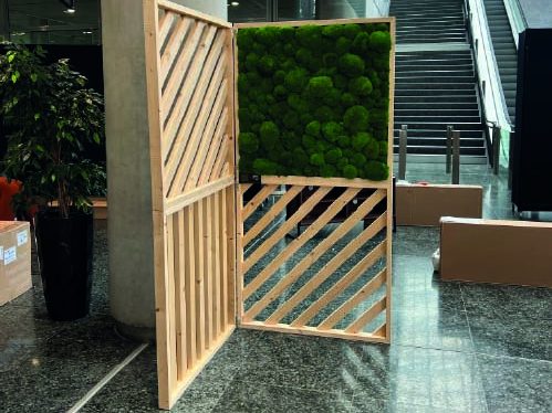 Panneau en bois avec une section de mousse verte et un design à lattes.