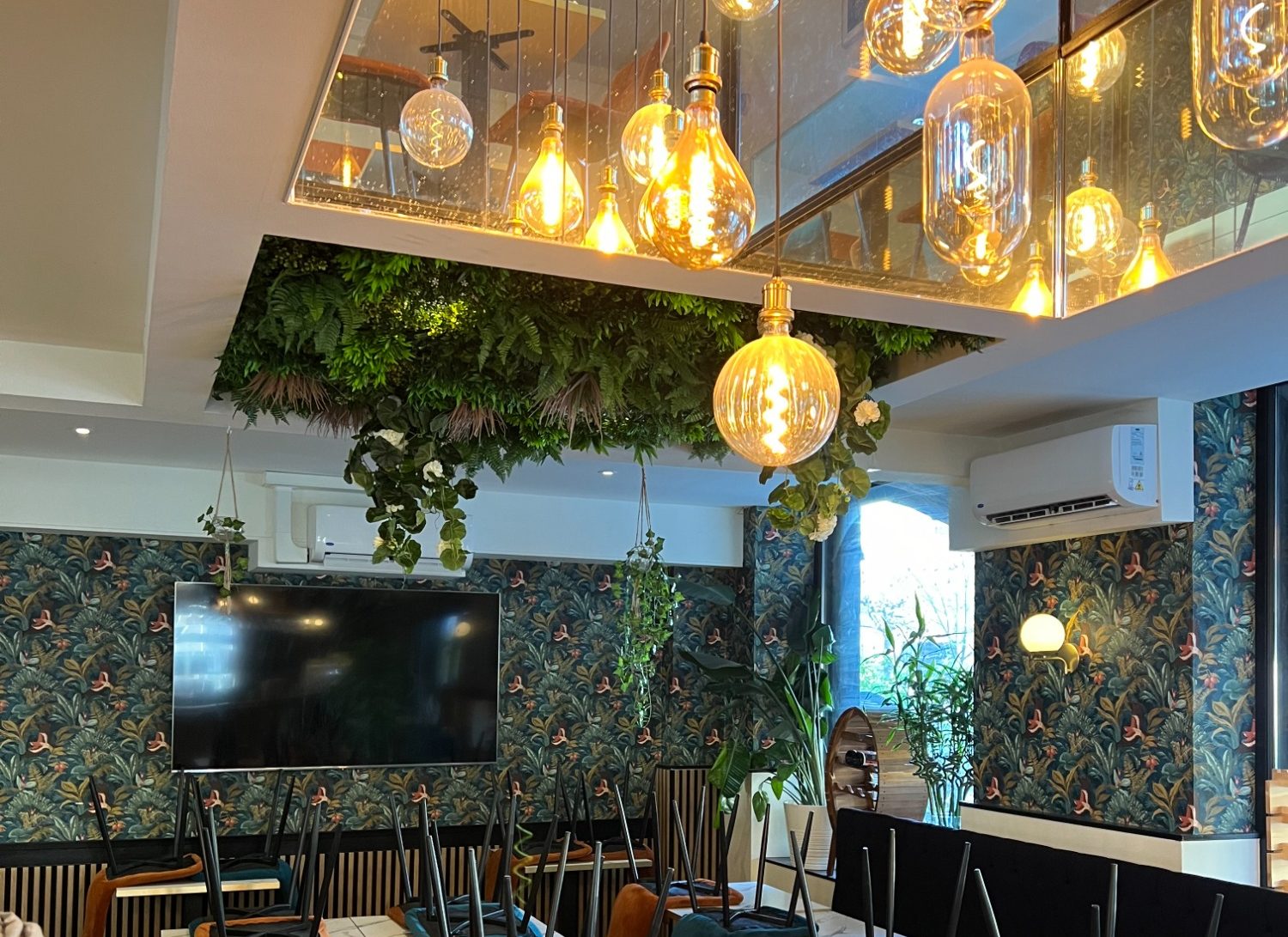 Intérieur d'un restaurant avec éclairage appliqué et décoration végétale.