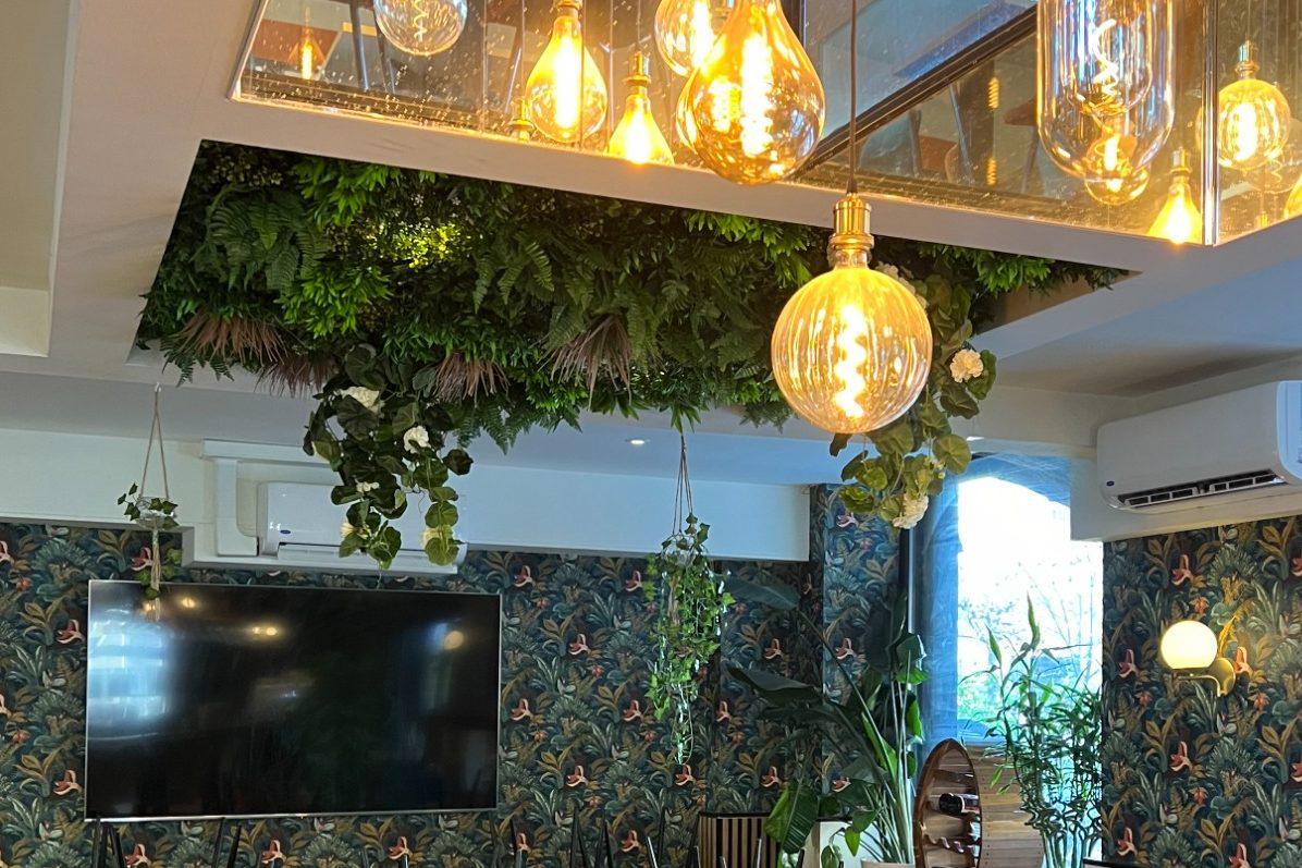 Logo en forme de cercle avec un motif de gazon, avec deux fauteuils gris à proximité.