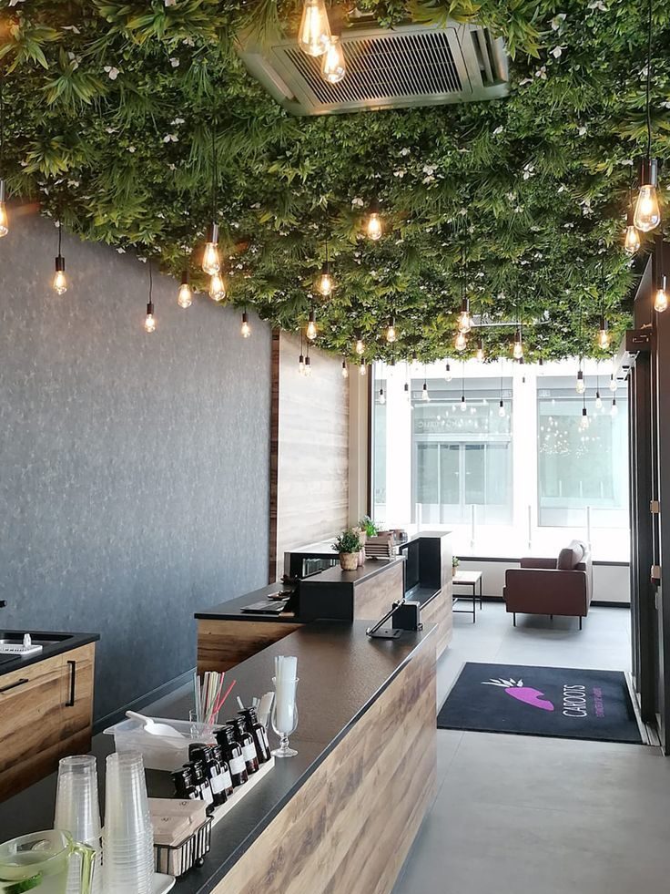 Intérieur moderne d'un café avec un plafond végétal et un éclairage chaleureux.